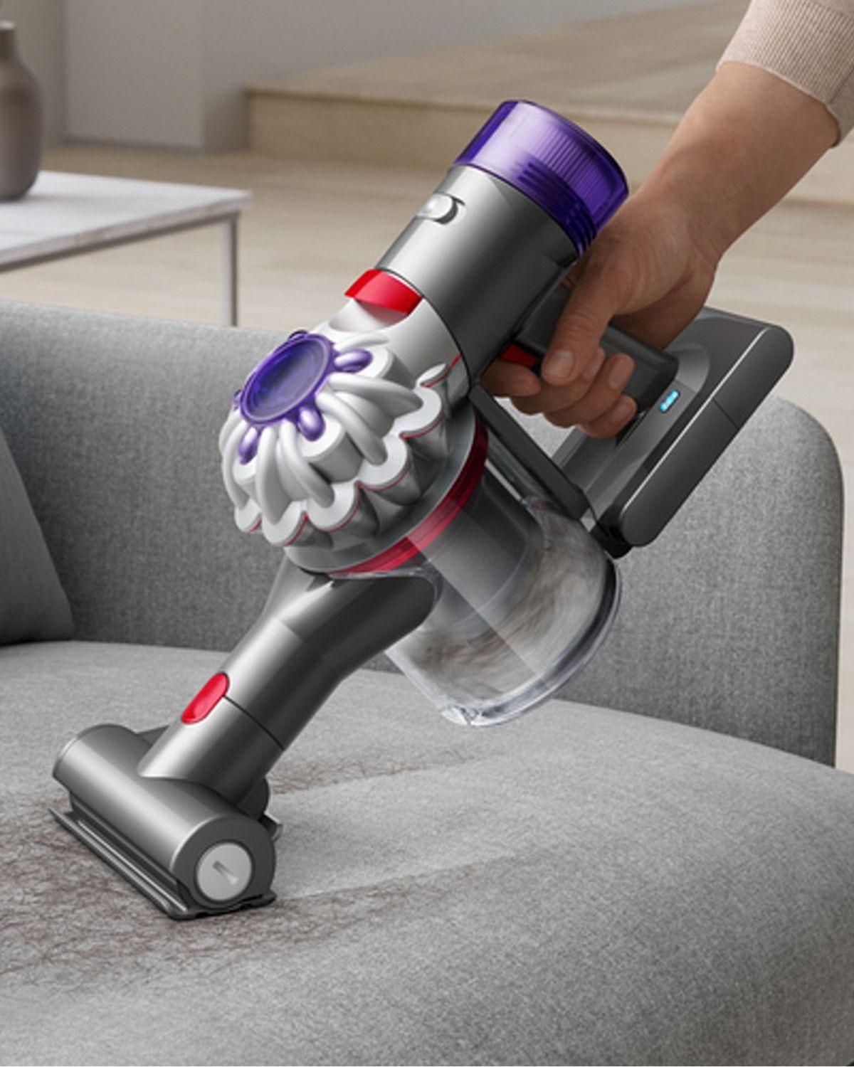 The Dyson Car+Boat handheld vacuum with the Mini motorised tool cleaning hair from a sofa.